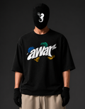 A person wearing a black oversized T-shirt with a large stylized 'awar' graphic in white, blue, green, and yellow, paired with a black face covering, black gloves, and beige pants, against a dark studio background.