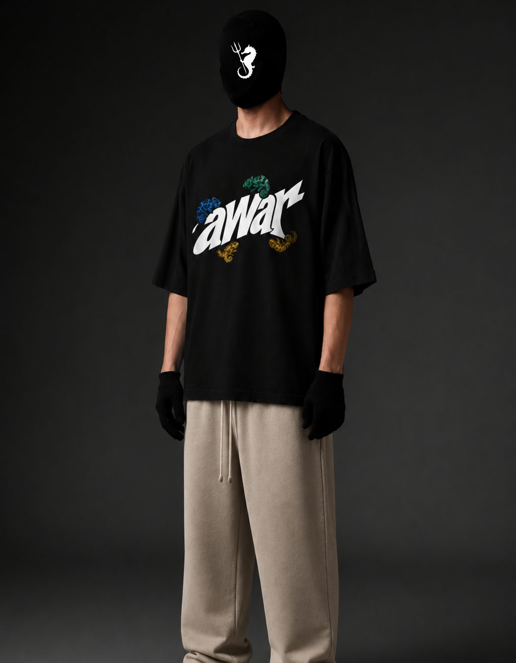A model wearing a black graphic t-shirt with a stylized 'awar' logo and colorful accents, paired with beige drawstring sweatpants, black gloves, and a black balaclava mask, set against a dark gray studio background.