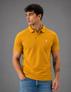 Man wearing a mustard yellow polo shirt with a logo on a gray background