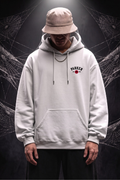 A person wearing a light gray pullover hoodie with a drawstring hood and kangaroo pocket, a beige bucket hat, and dark pants, standing against a dark background with spiderweb graphics. The hoodie has a small chest graphic reading 'PARKER' with a red circle logo.