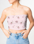 Person wearing a pink strapless top with strawberry pattern and blue jeans on a light gray background