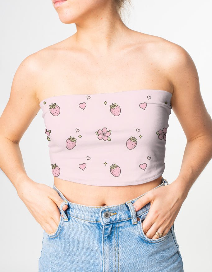 Person wearing a pink strapless top with strawberry pattern and blue jeans on a light gray background