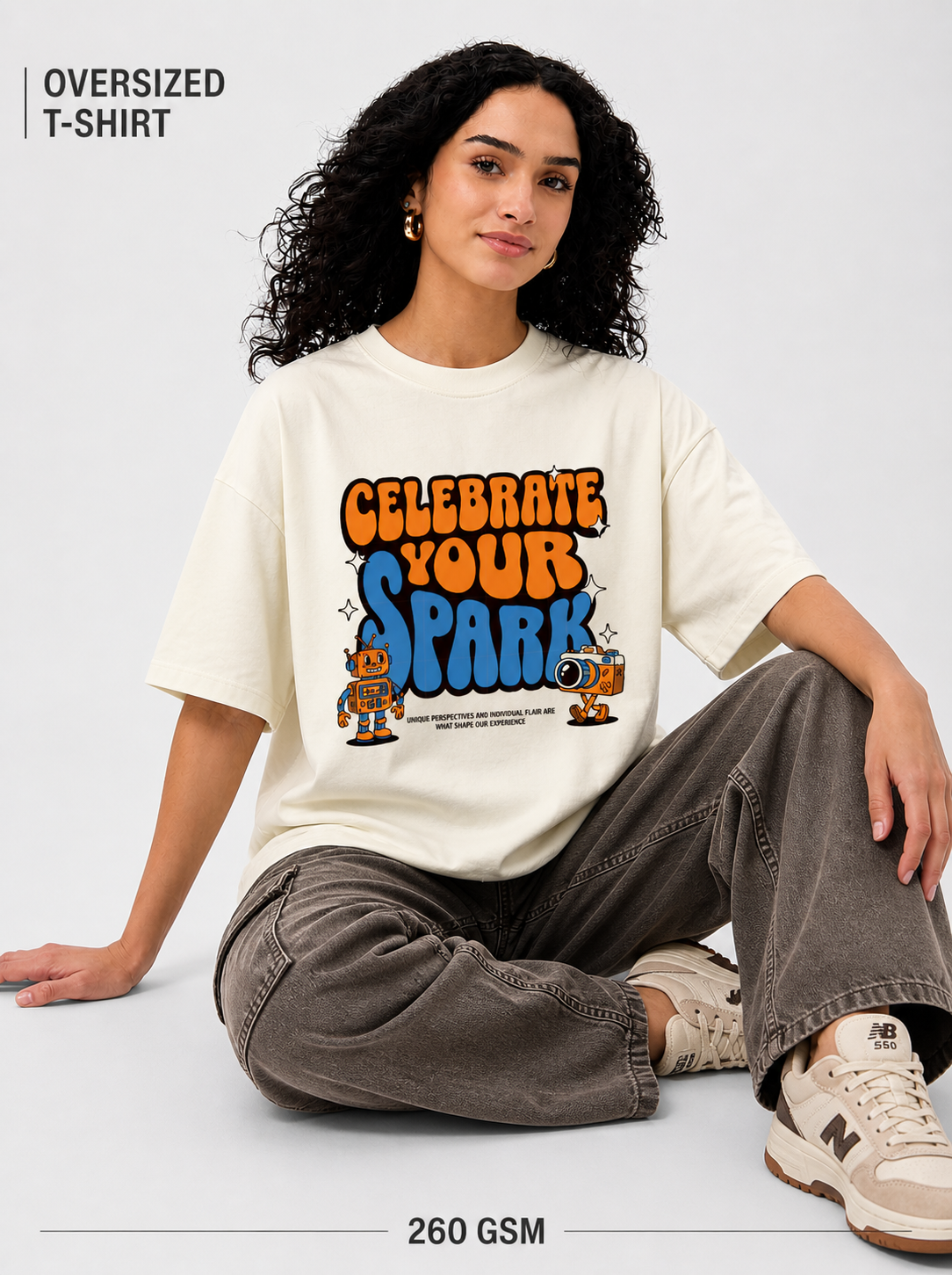Person wearing an oversized t-shirt with 'Celebrate Your Spark' text and graphics on a light gray background.