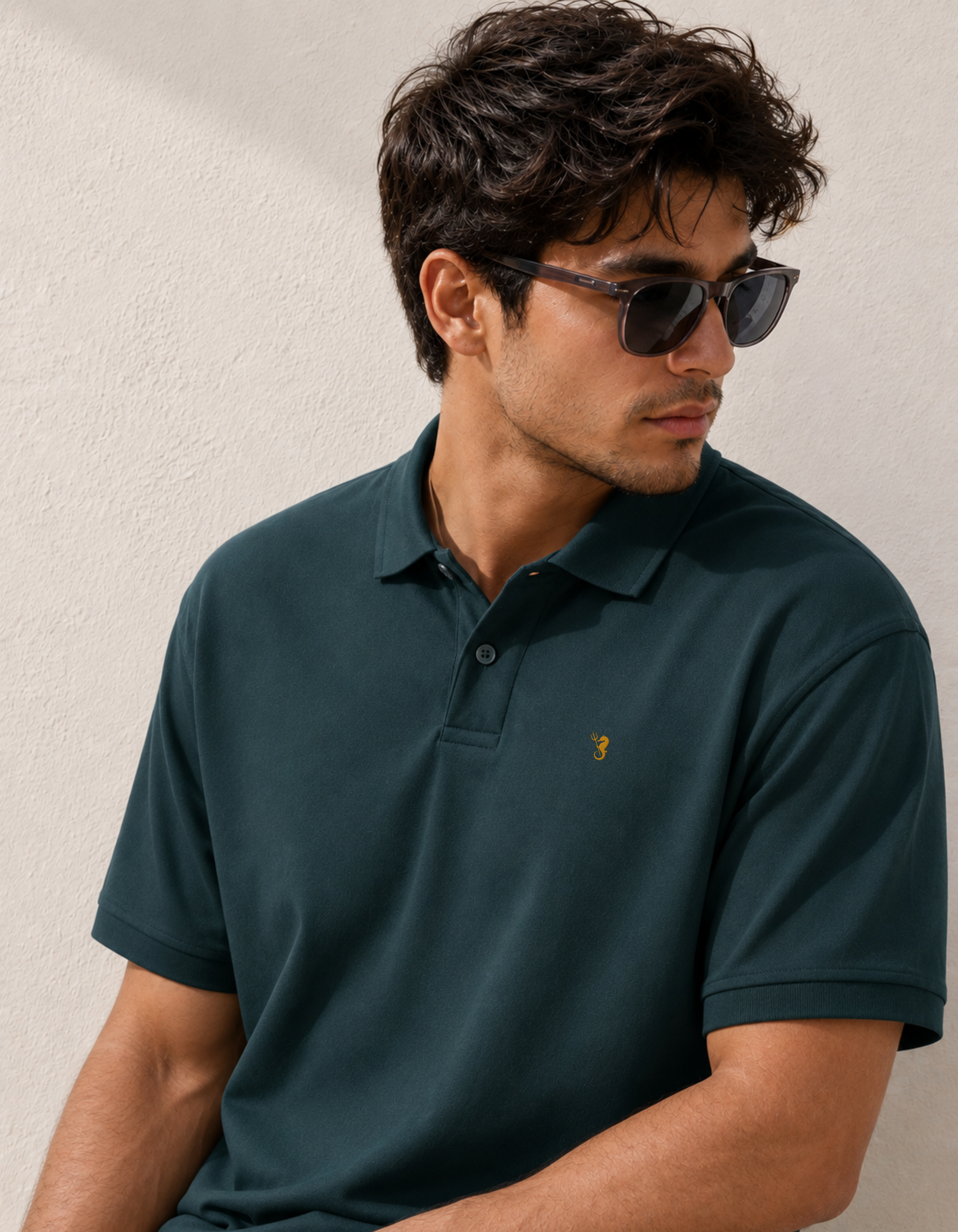 Man wearing a dark green polo shirt with a logo against a neutral background