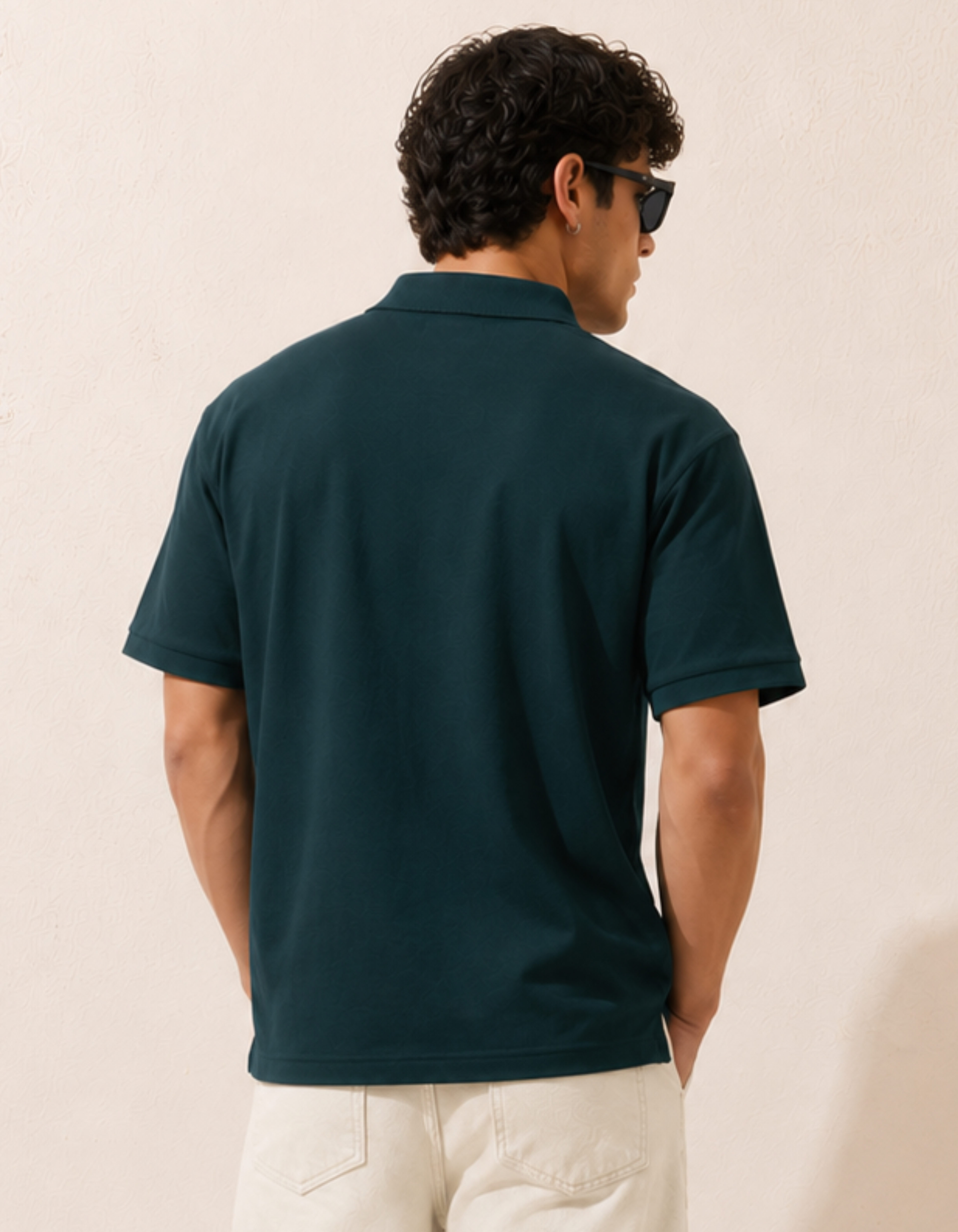 Man wearing a dark green polo shirt against a beige background