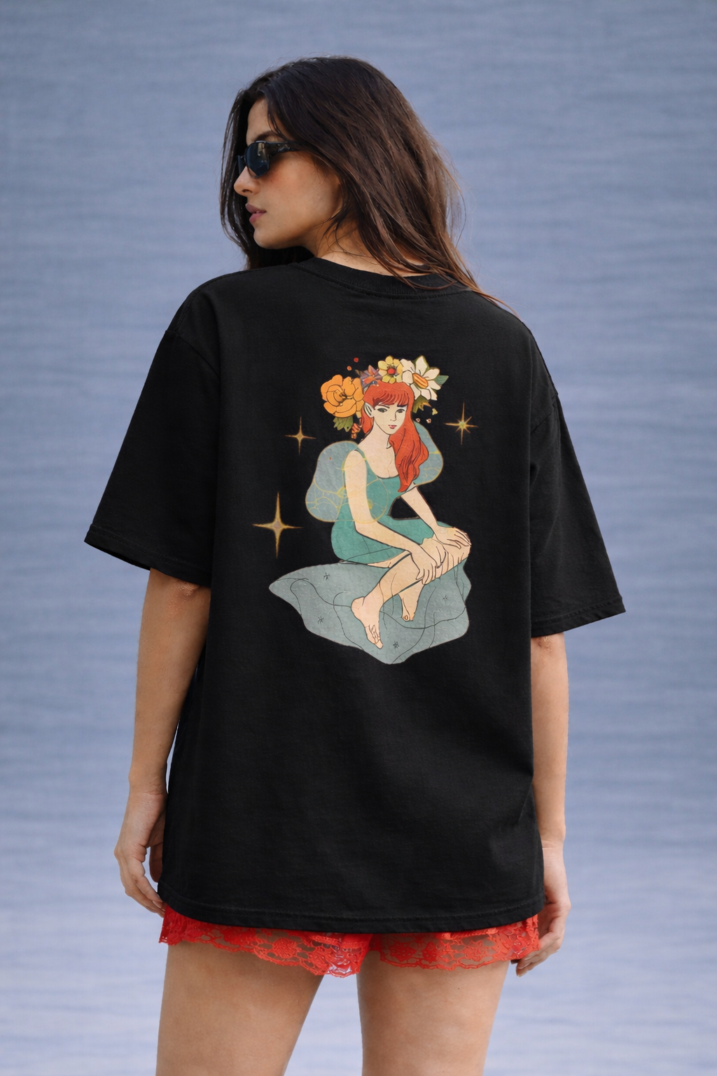 Person wearing a black t-shirt with a colorful graphic design on a textured blue background