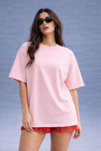 Woman wearing a pink oversized t-shirt and red shorts against a gray background