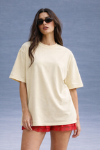 Woman wearing a beige oversized t-shirt and red shorts against a gray background