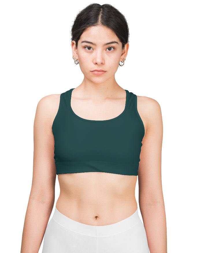 Woman wearing a green sports bra and white pants on a white background
