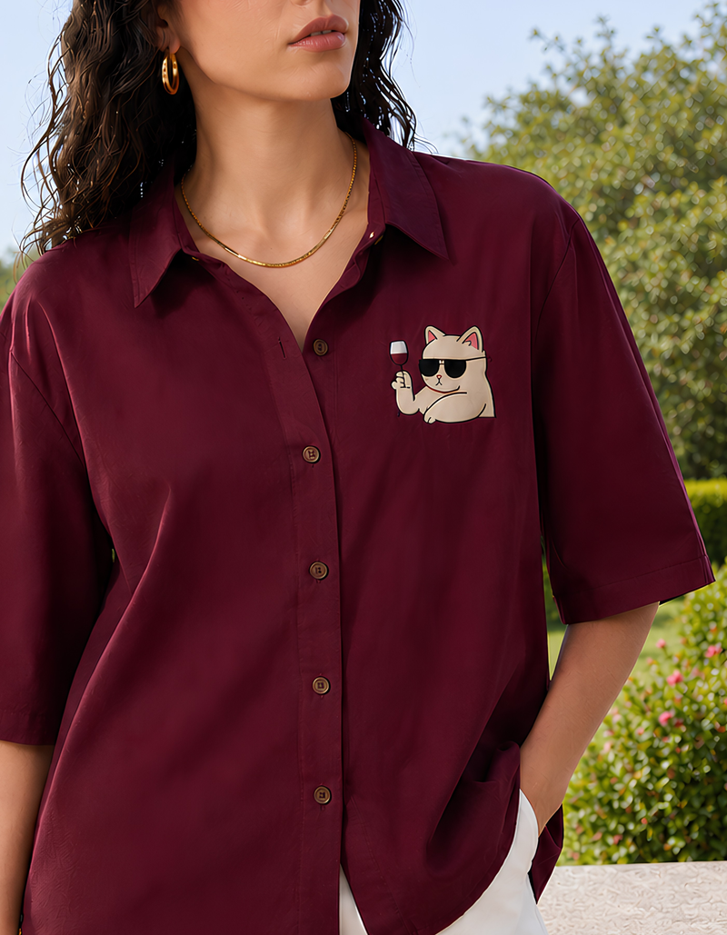 Woman wearing a maroon shirt with a cat graphic outdoors