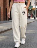 Person wearing cream sweatpants with a cat graphic on a city street