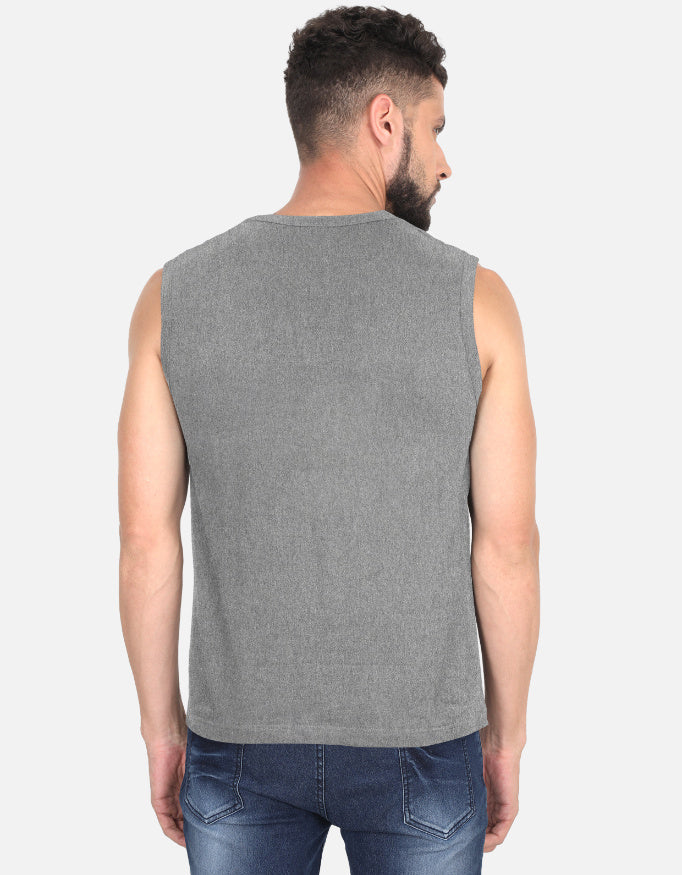 Man wearing a gray sleeveless shirt and blue jeans on a white background