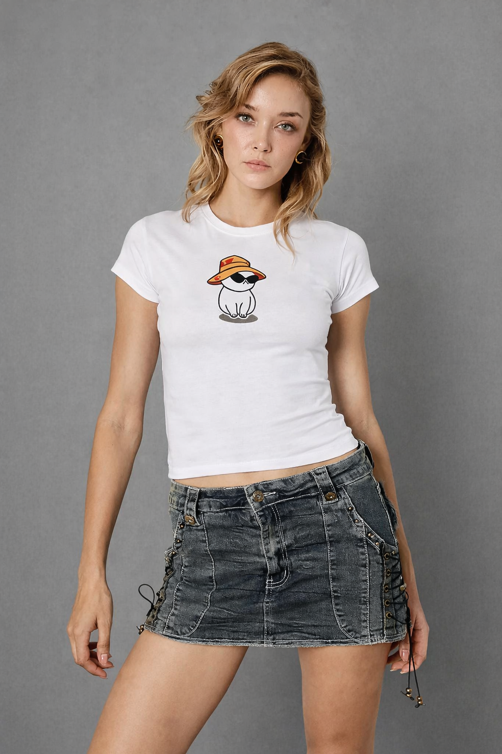 Woman wearing a white t-shirt with a graphic design and a denim skirt on a gray background