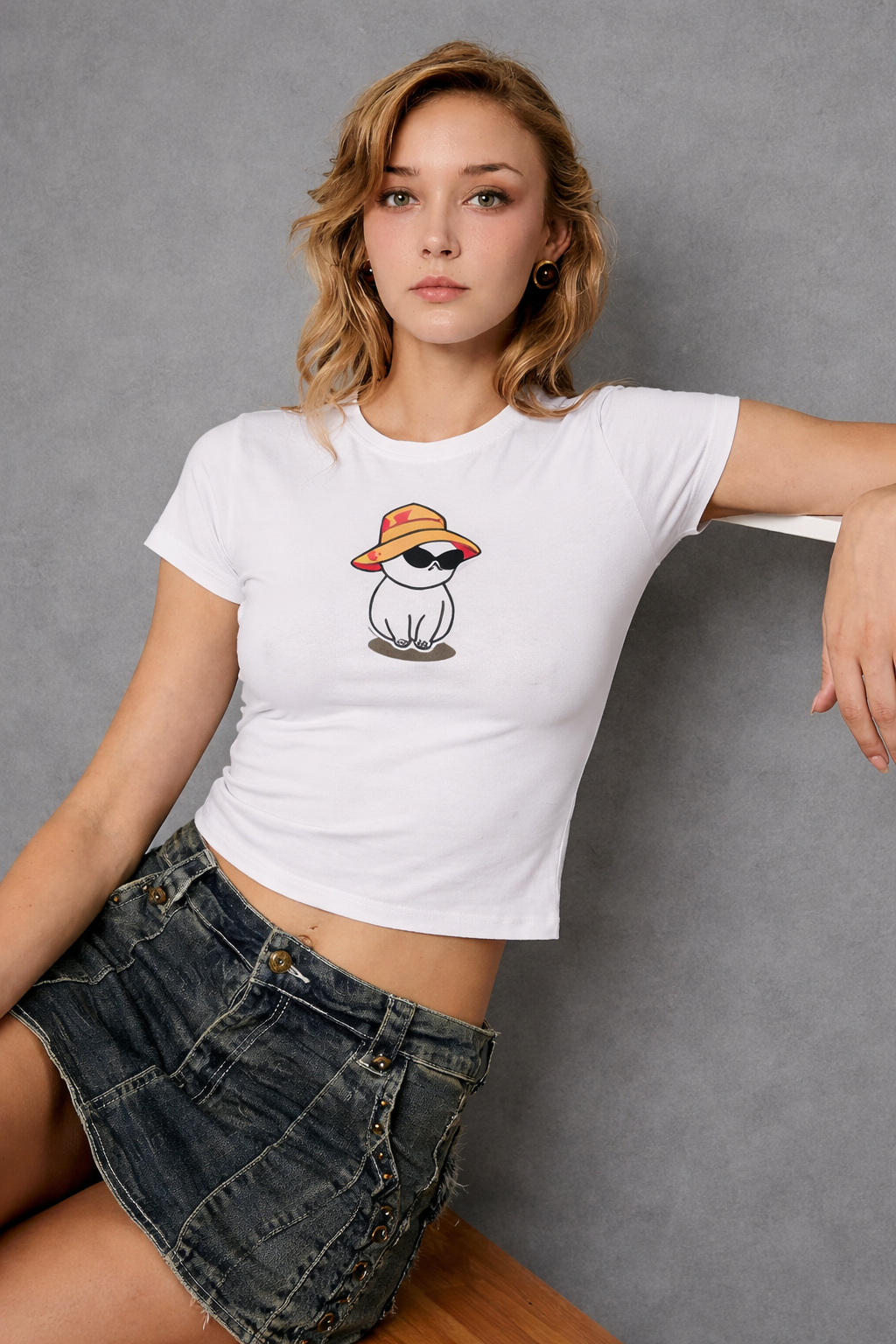 Woman wearing a white t-shirt with a graphic design of a dog wearing a hat against a gray background