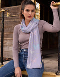 Woman wearing a light purple scarf with butterfly patterns, sitting on a wooden staircase.