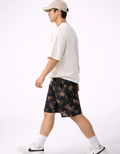 Person wearing a white t-shirt and black tie-dye shorts on a white background