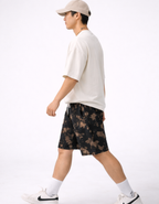 Person wearing a white t-shirt and black tie-dye shorts on a white background
