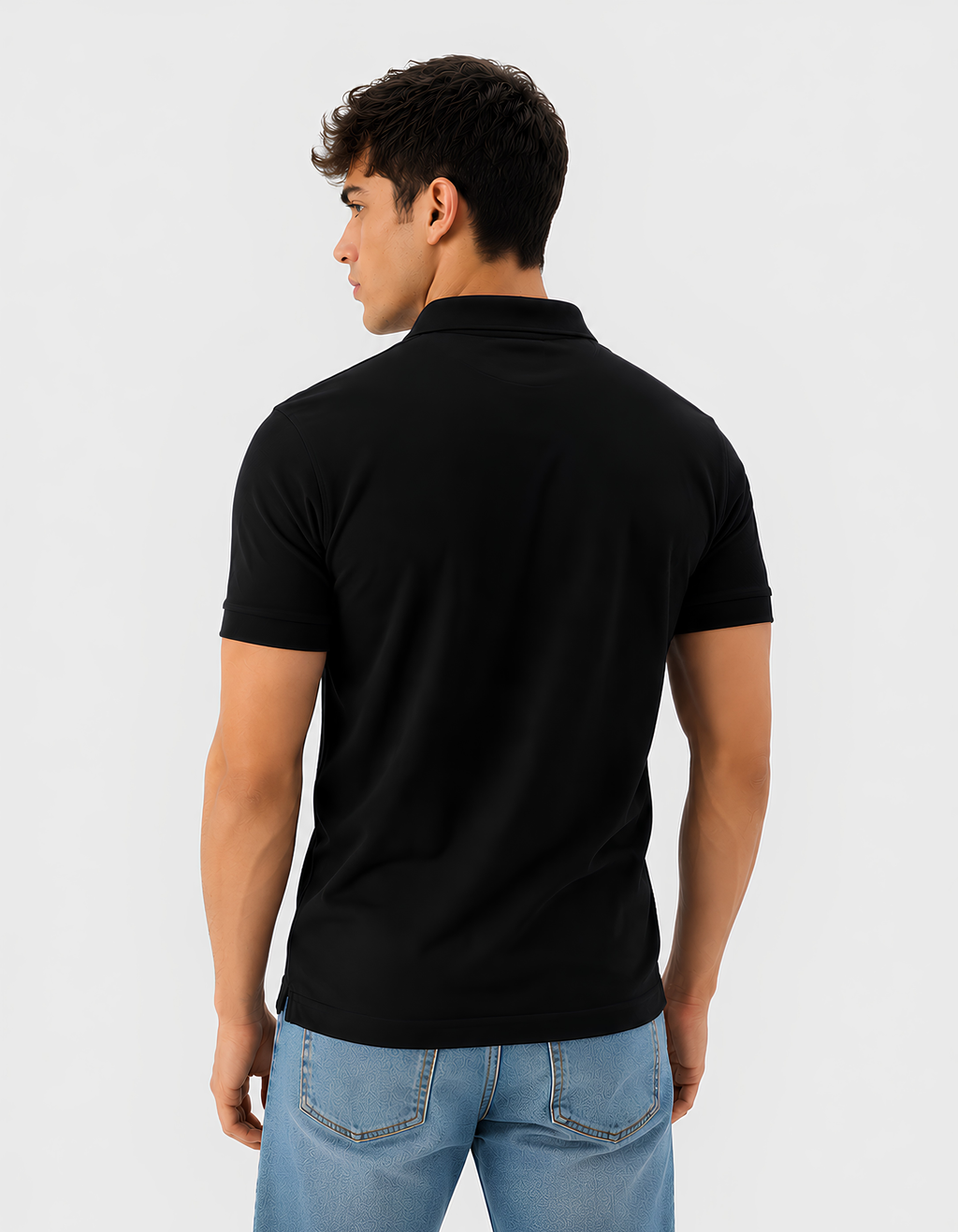 Man wearing a black polo shirt and blue jeans on a light gray background