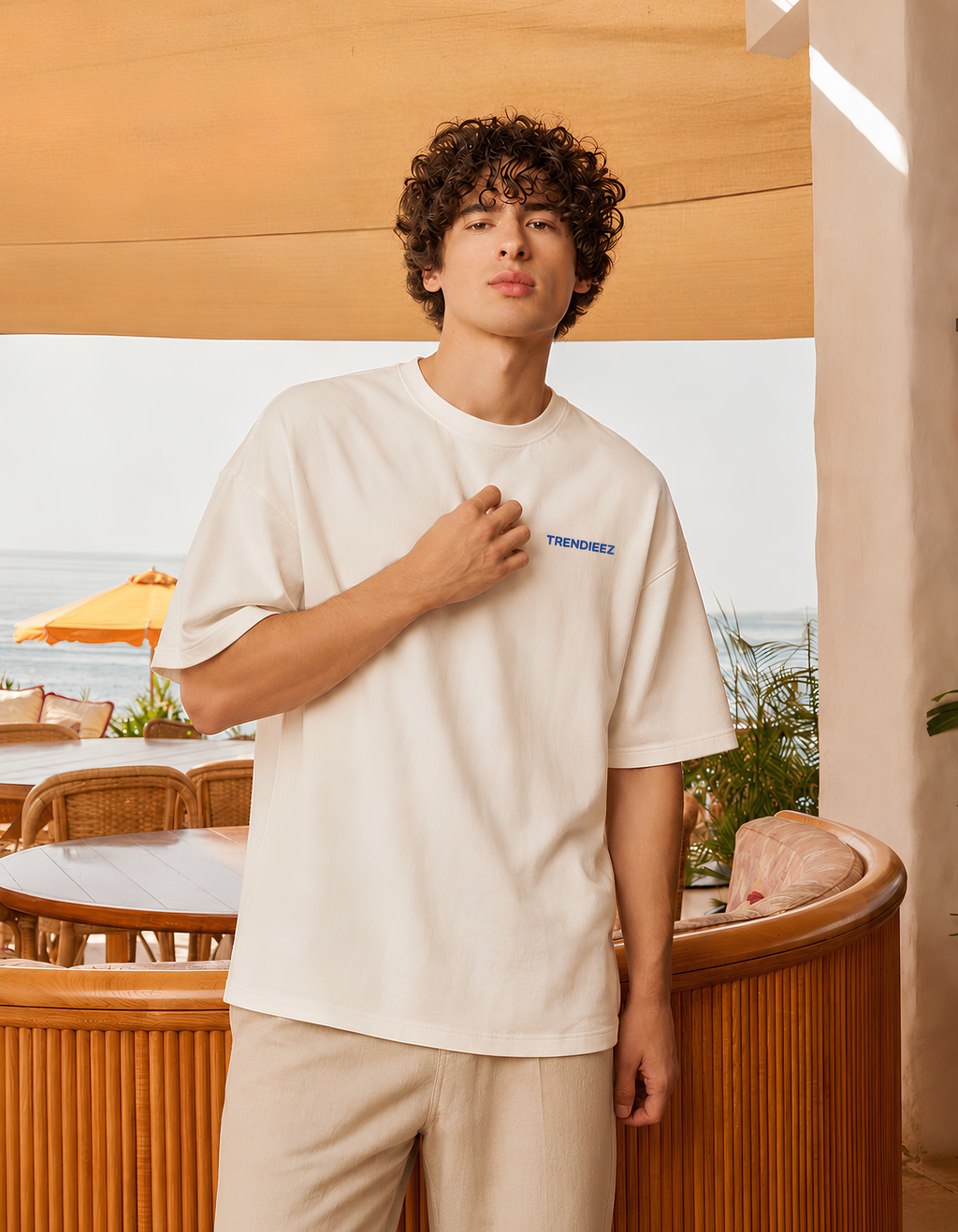 Man wearing a beige t-shirt with a logo in an outdoor setting