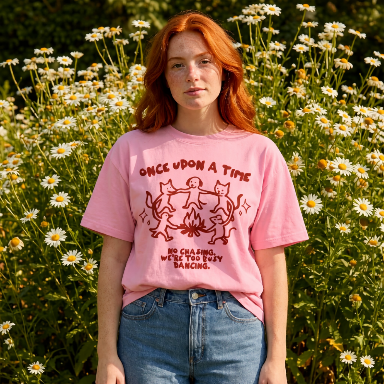 Person wearing a pink t-shirt with a graphic design in a field of flowers