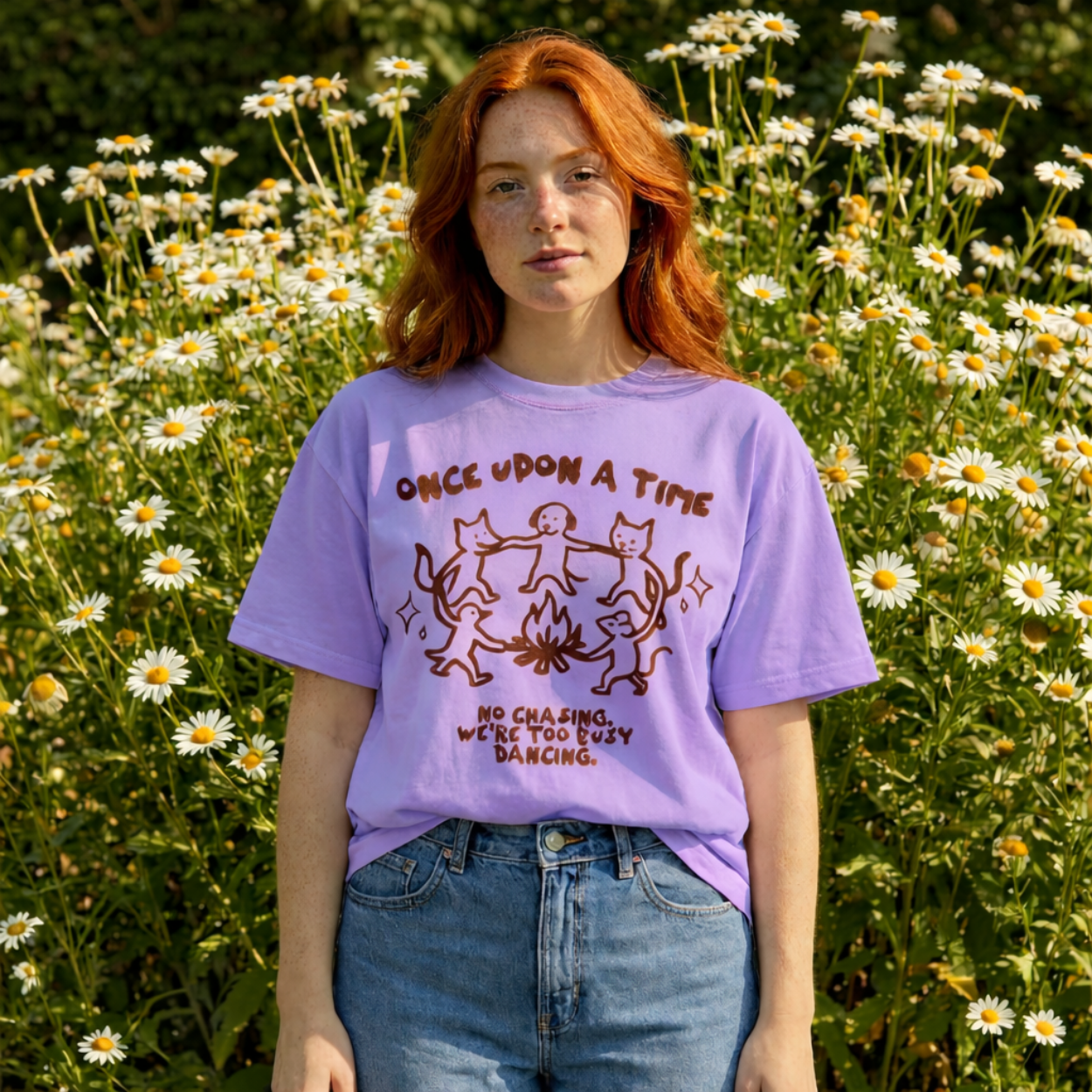 Person wearing a purple t-shirt with a graphic design in a field of flowers