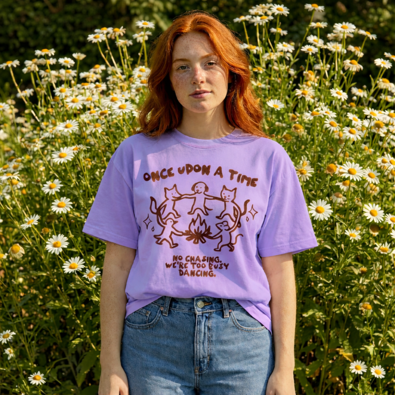 Person wearing a purple t-shirt with a graphic design in a field of flowers