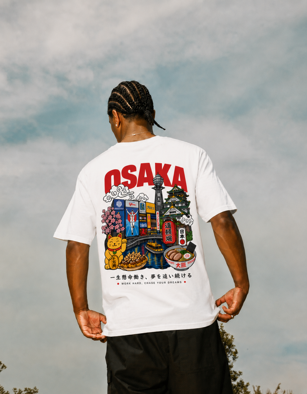 Person wearing a white t-shirt with Osaka-themed graphics against a cloudy sky.