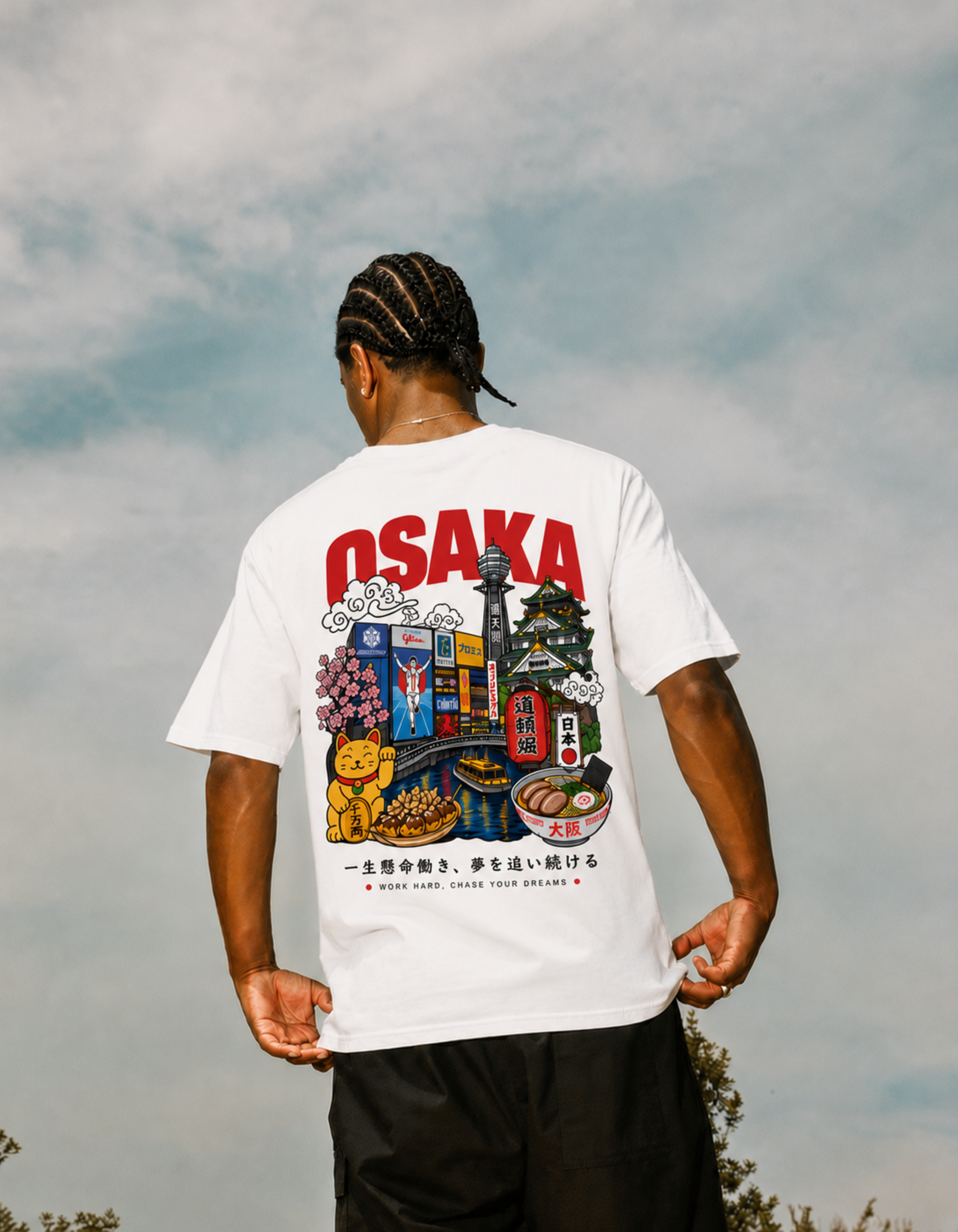 Person wearing a white t-shirt with Osaka-themed graphics against a cloudy sky.