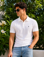 Man wearing a white polo shirt and sunglasses with a green foliage background