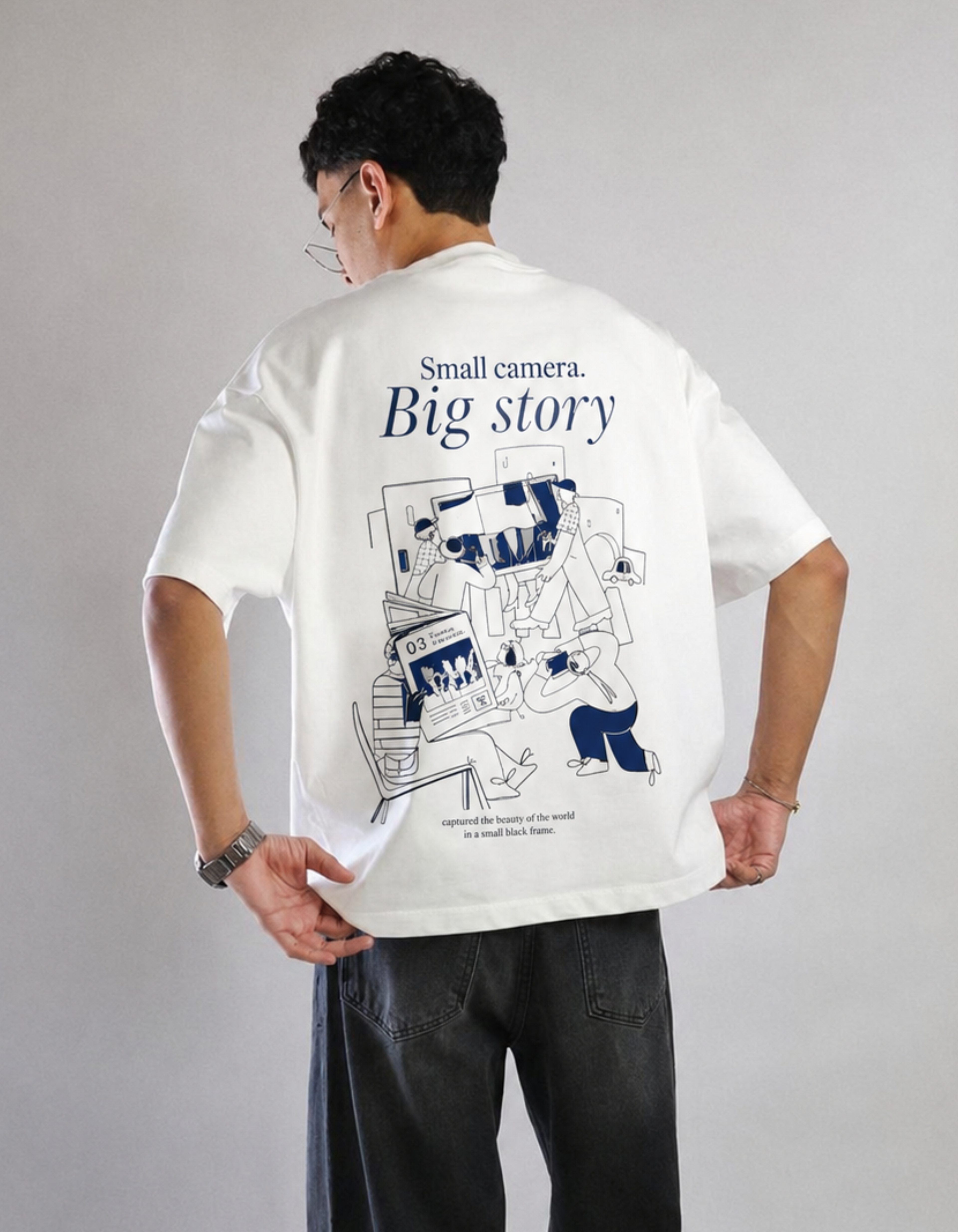 Person wearing a white t-shirt with a graphic design and text on the back, standing against a plain background.