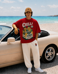 Person wearing a red 'Chill Summer' t-shirt leaning against a car on a beach.