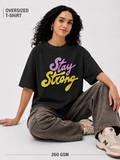 Person wearing an oversized t-shirt with 'Stay Strong' text, sitting on a light gray background.