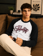 Man sitting on a couch wearing a black and white baseball shirt with 'Freddies' printed on it.