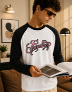 Man wearing a black and white 'Trendieez' shirt, holding an open book in a cozy living room.