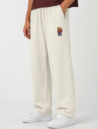 Person wearing cream sweatpants with a teddy bear patch on a white background